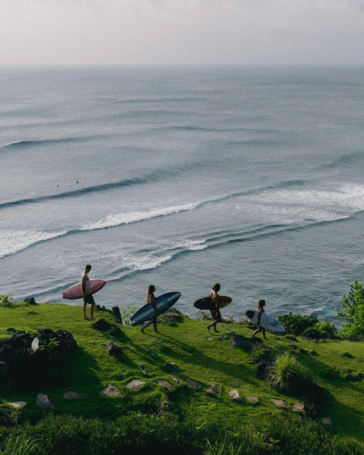 Friends walking down the cliff, going to surf
