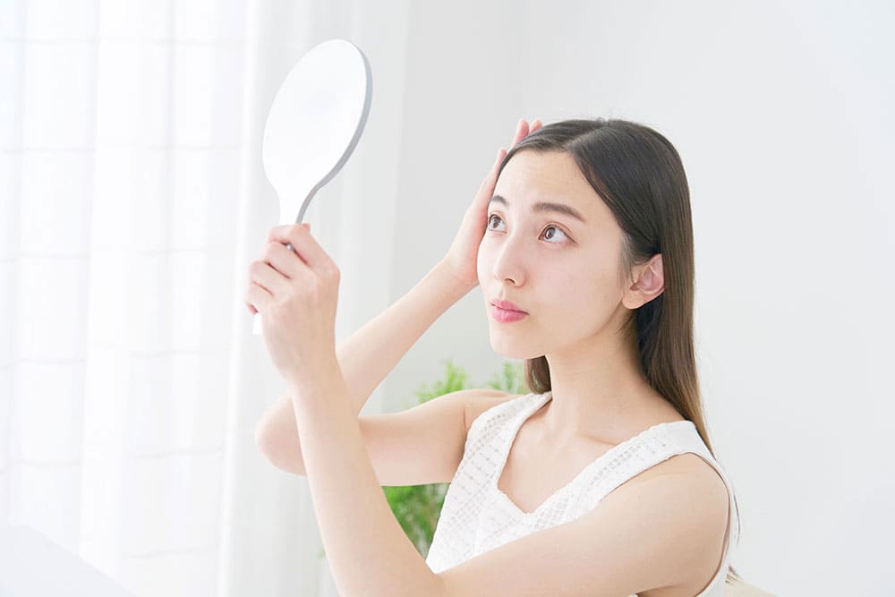 鏡で頭皮を確認する女性