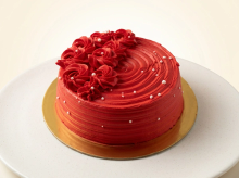 Deep red buttercream cake with piped rosettes and sugar pearls on a gold board