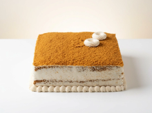 Square Lotus Biscoff cake dusted with crushed Biscoff, with cream rosettes and piped cream borders