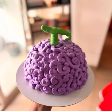 Sculpted One Piece Devil Fruit cake with purple buttercream swirl pattern and green fondant stem