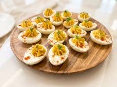 Deviled eggs with piped spiced yolk and paprika on a wooden board