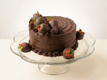 Dark chocolate ganache cake layered with fresh strawberry, decorated with chocolate-dipped strawberries and piped rosettes
