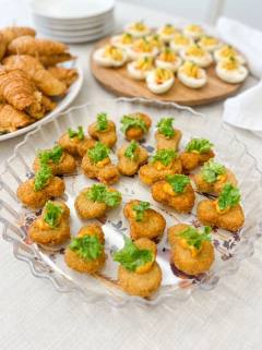 Fried chicken bites topped with chipotle sauce and fresh greens on a platter