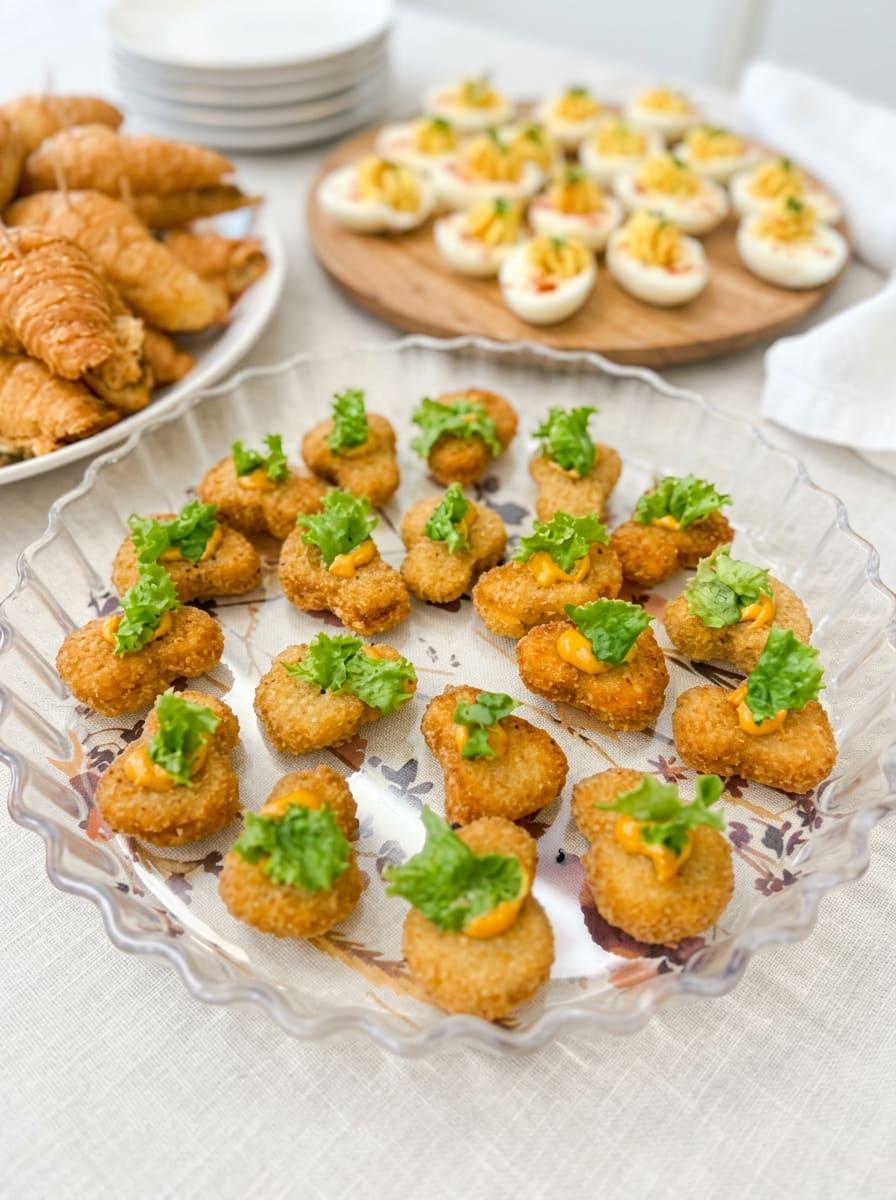 Fried chicken bites topped with chipotle sauce and fresh greens on a platter
