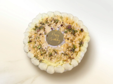 Rasmalai cake with saffron sponge, garnished with a cream wreath and crushed pistachios