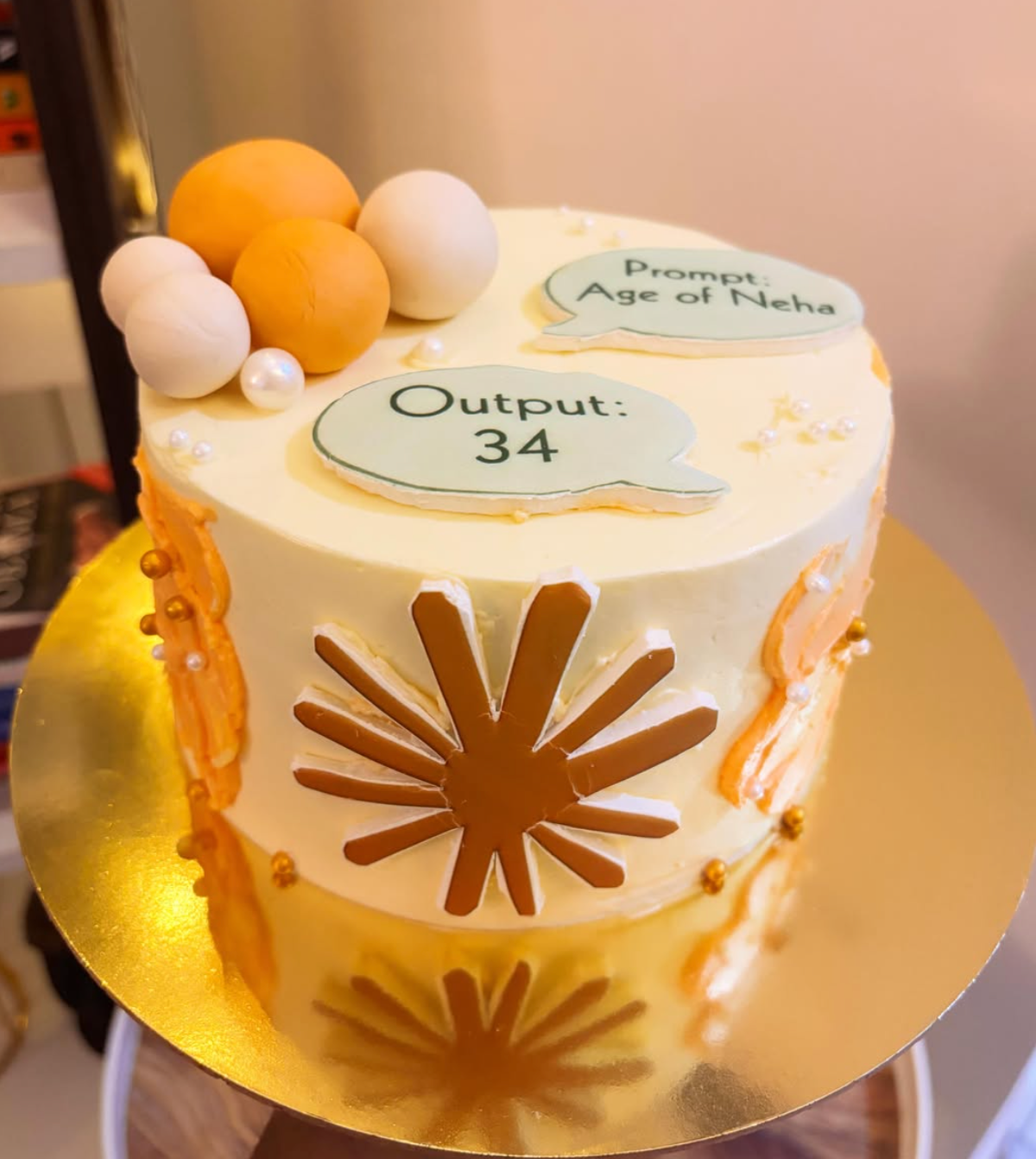 Custom tech-themed birthday cake with prompt and output speech bubbles, gold accents and sunburst chocolate decorations