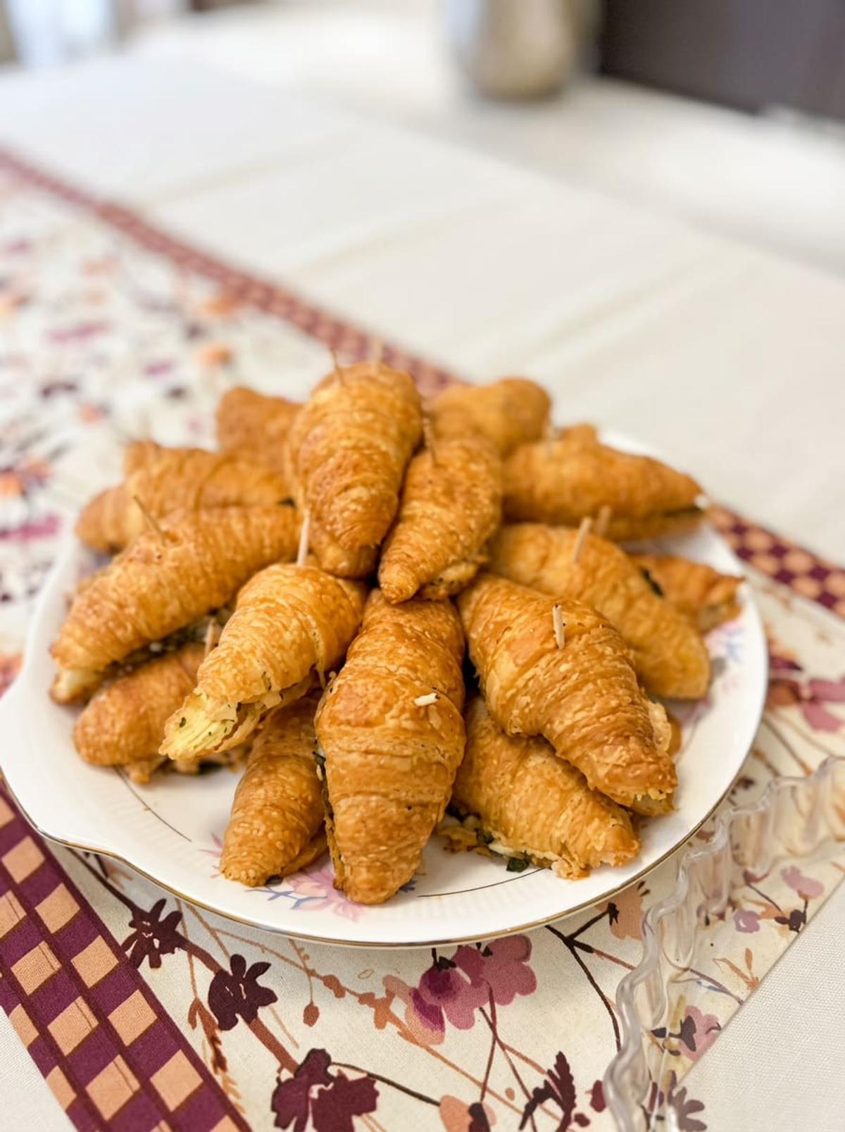 Mini stuffed croissants stacked on a floral plate