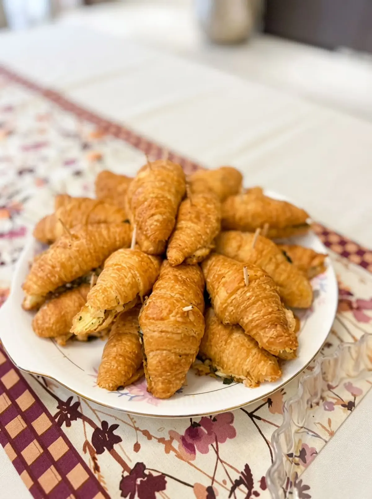 Mini stuffed croissants stacked on a floral plate