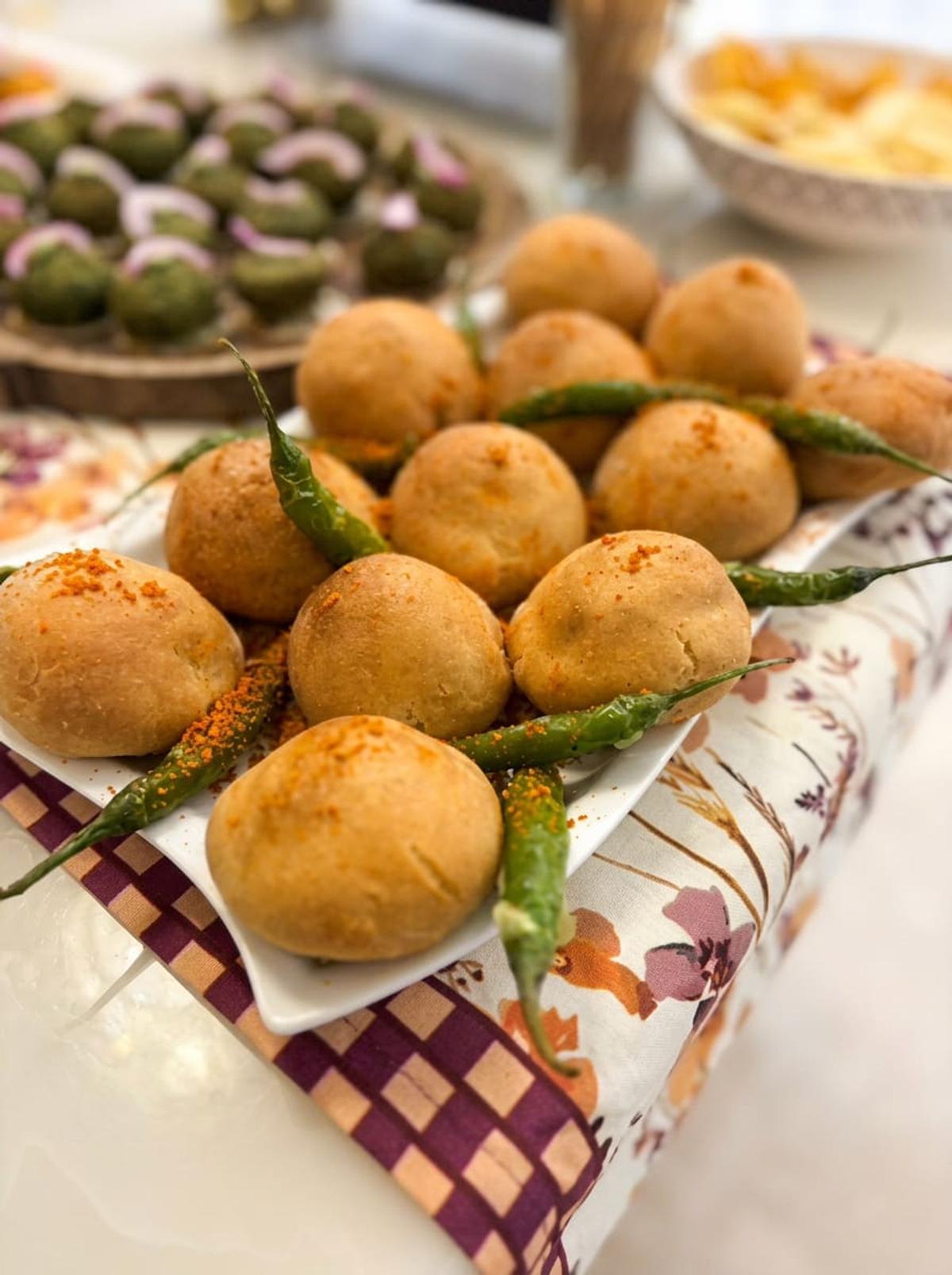 Savoury besan bites garnished with green chillies on white platters