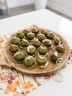Green herb kebab bites on crackers with pickled onion on a wooden board