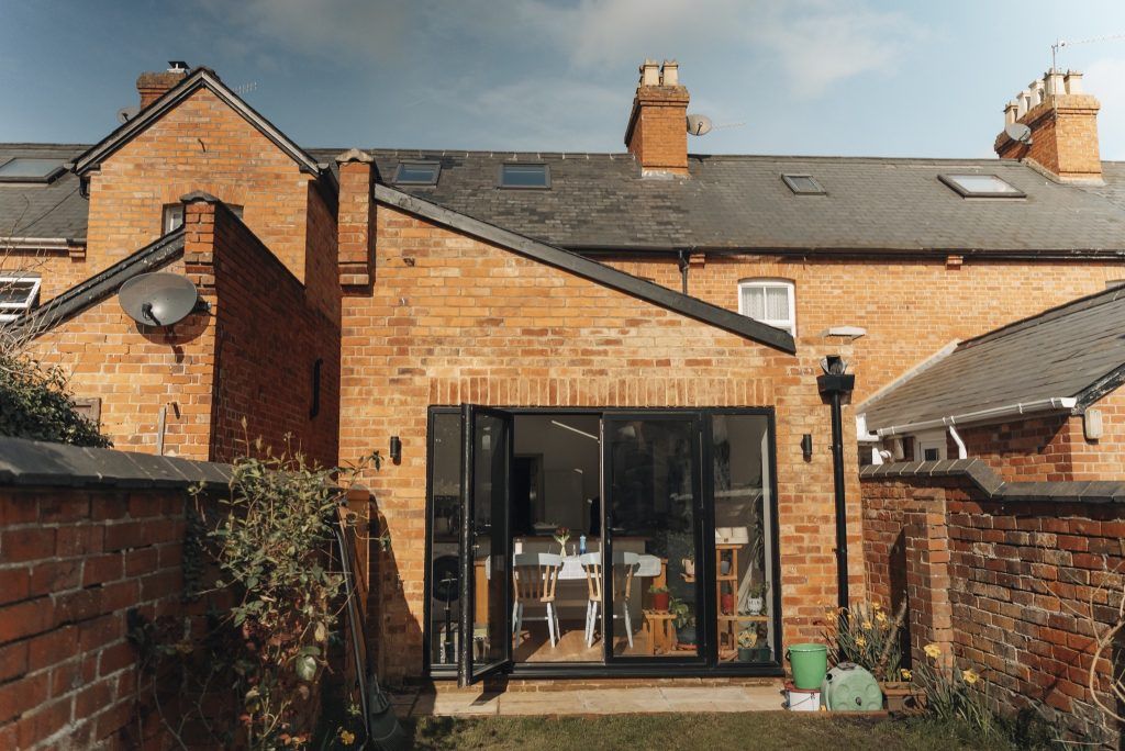 Red-brick house with a modern glass extension by Prestige Surrey