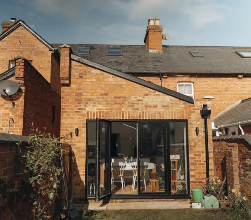 Red-brick house with a modern glass extension by Prestige Surrey