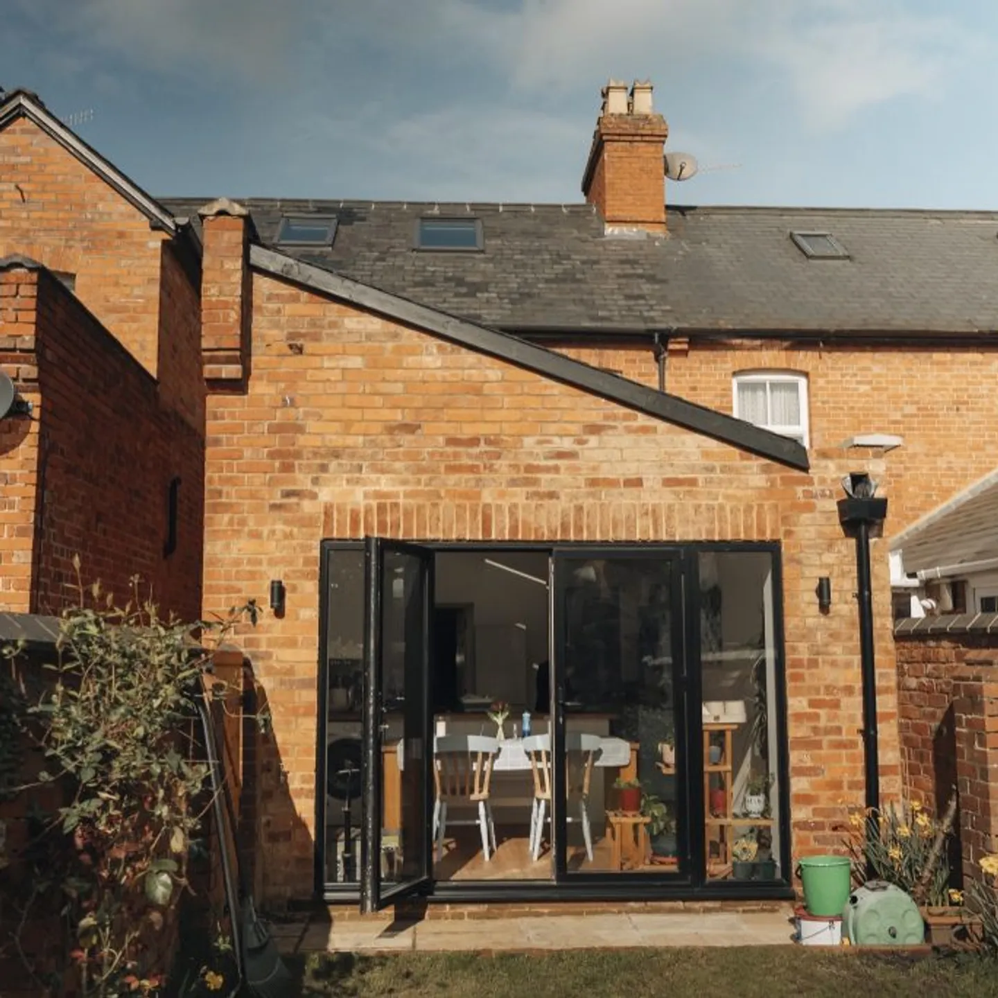 Red-brick house with a modern glass extension by Prestige Surrey
