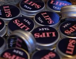 LIPS TASK logo på en samling runde bokser leppepomader.