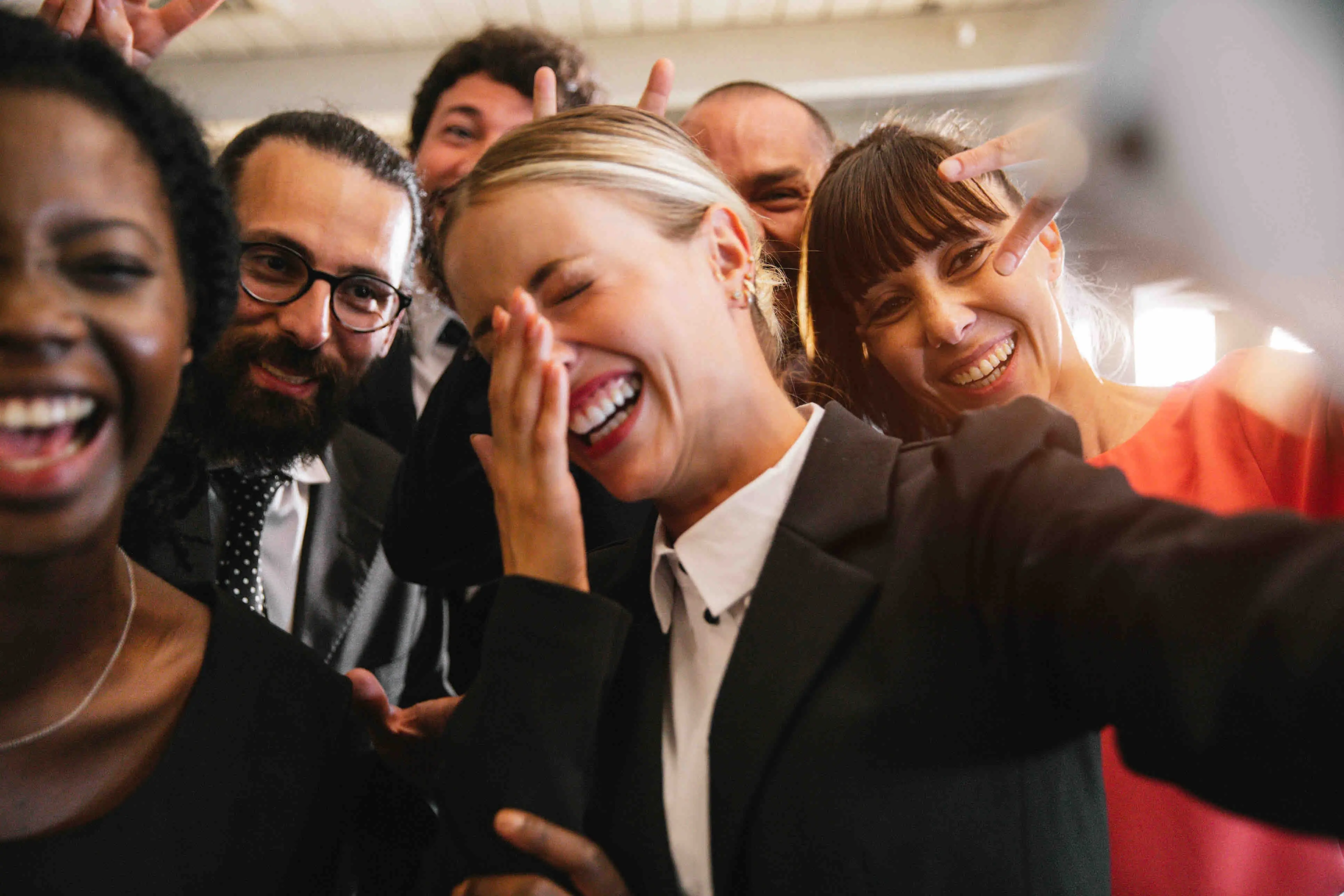 Groupe de collègues souriants prenant un égoportrait dans une ambiance conviviale et professionnelle.