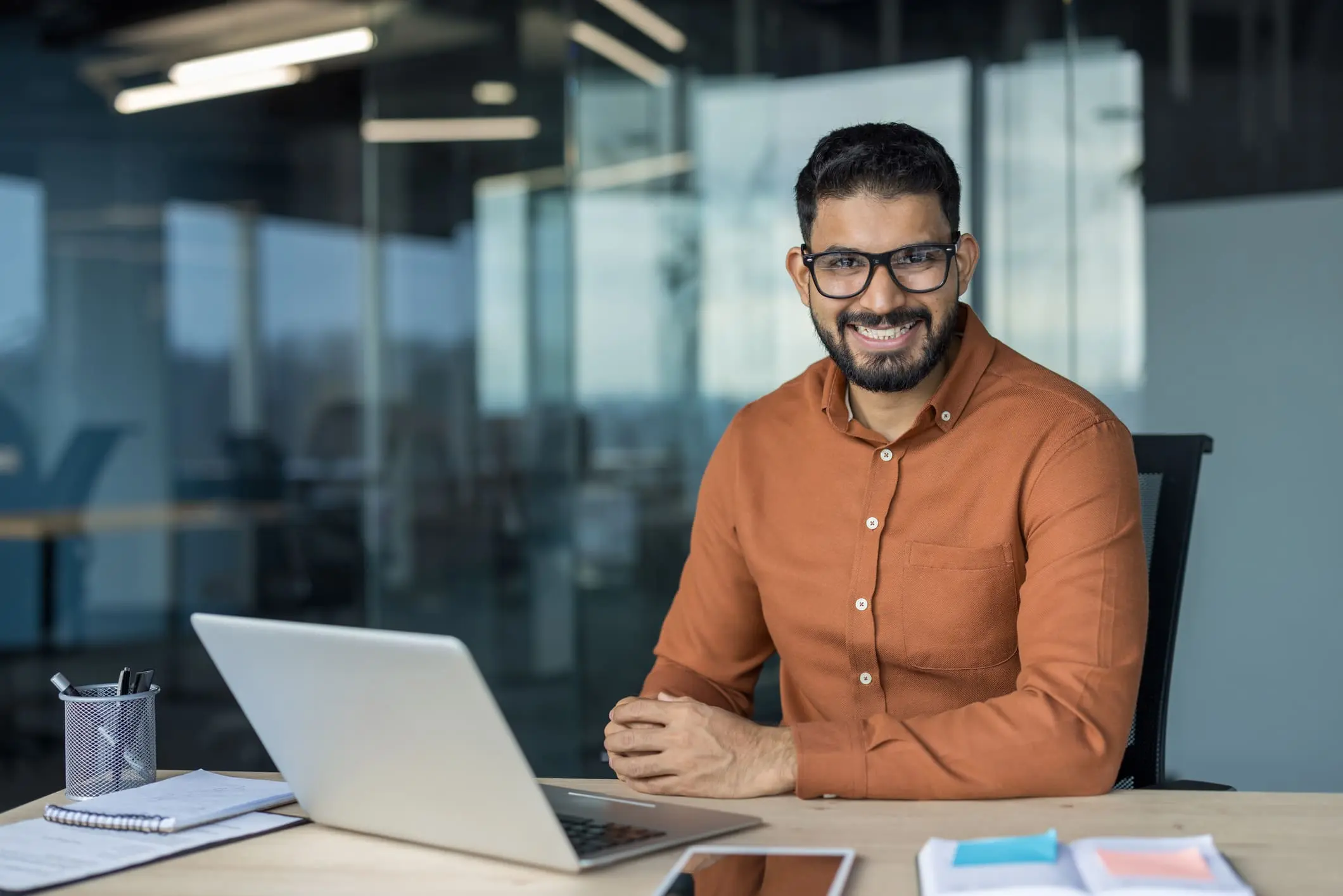 Homme devant ordinateur souriant à la caméra