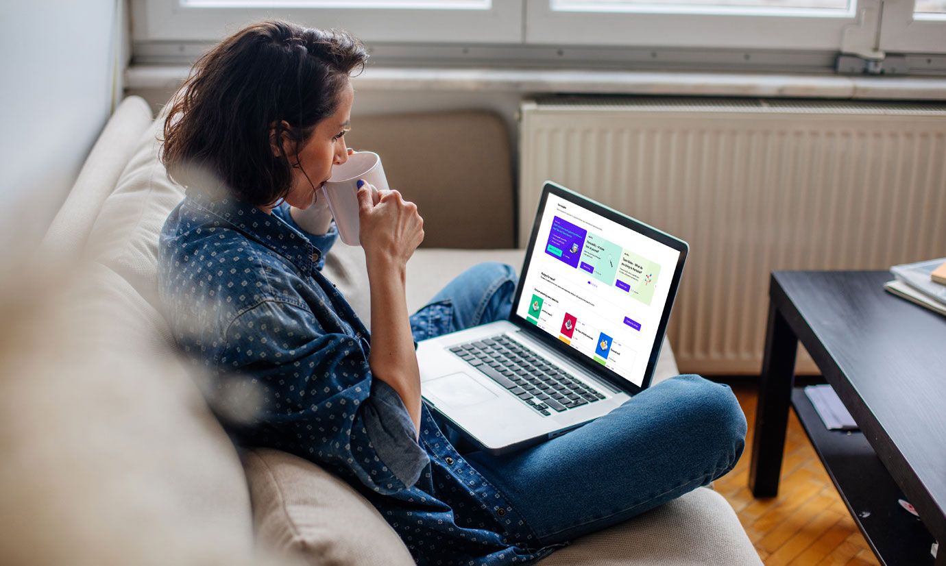 Frau trinkt Kaffee und betrachtet die Goodhabitz-Plattform auf dem Laptop