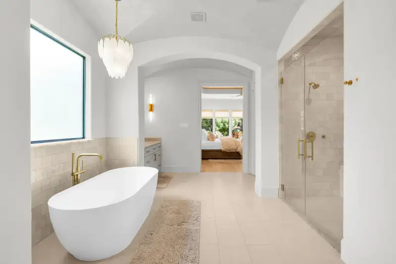 Primary bath with a freestanding tub below a frosted window, beside a glass-enclosed shower.