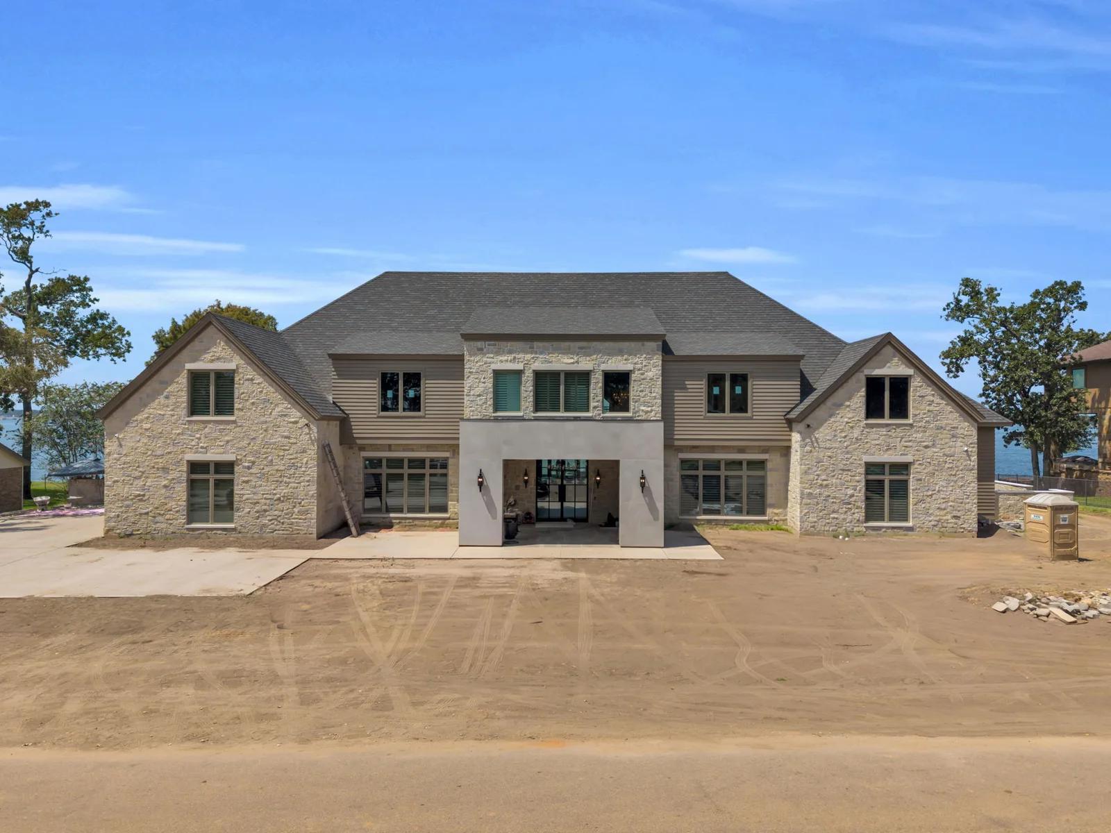 Front elevation of the Escondido home with stone and tan lap siding under a gray shingle roof.