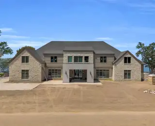 Front elevation of the Escondido home with stone and tan lap siding under a gray shingle roof.