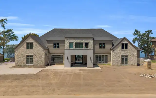 Front elevation of the Escondido home with stone and tan lap siding under a gray shingle roof.