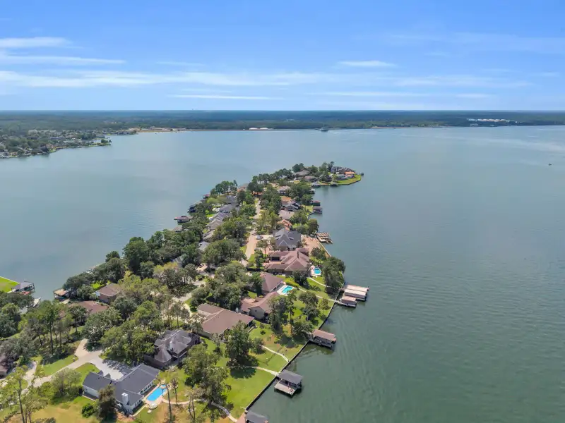 Aerial view of a wooded peninsula with homes and boat docks extending into a large lake.