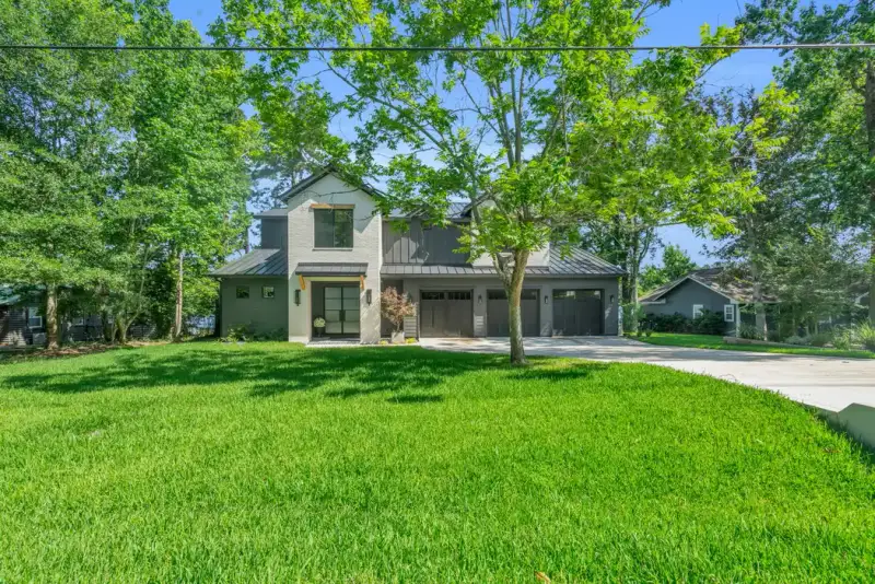 Front view of the Southshore home across a green lawn, with three garage doors and mature trees.