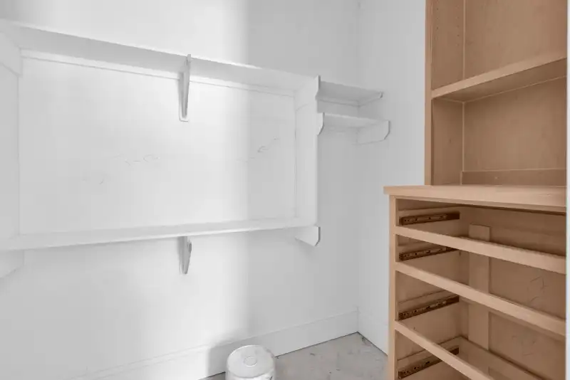 Pantry or closet with white wall shelving and a wood unit with drawer slides.