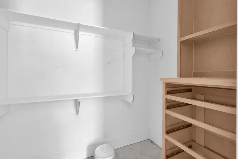Pantry or closet with white wall shelving and a wood unit with drawer slides.
