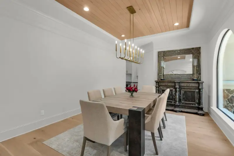 Dining room with a wood plank ceiling, a rectangular dining table, upholstered chairs, and a dark carved sideboard.