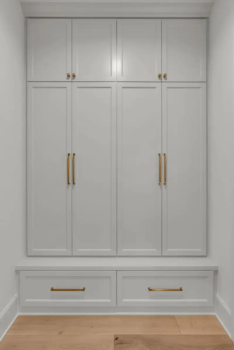 Tall gray built-in cabinets with brass pulls above a two-drawer base.