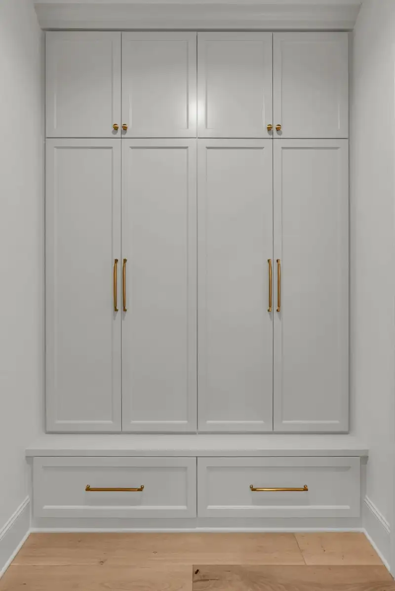 Tall gray built-in cabinets with brass pulls above a two-drawer base.