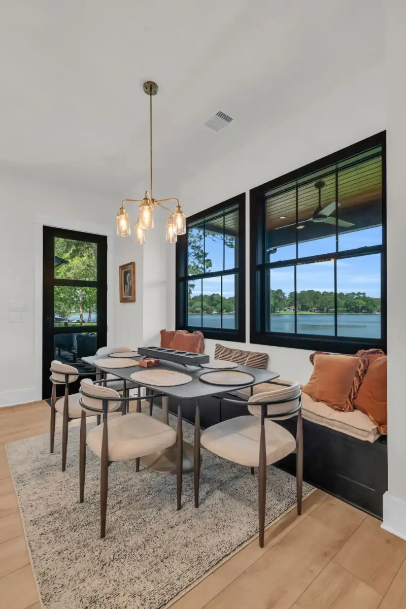 Dining nook with a dark table, upholstered chairs, a bench seat, and windows overlooking water.