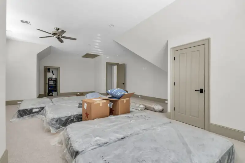 Upstairs room with carpet, a ceiling fan, and mattresses and boxes on the floor.