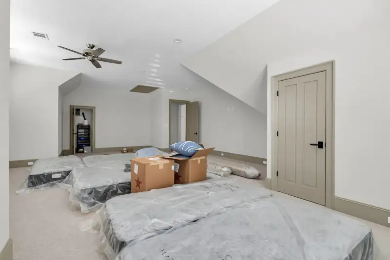 Upstairs room with carpet, a ceiling fan, and mattresses and boxes on the floor.