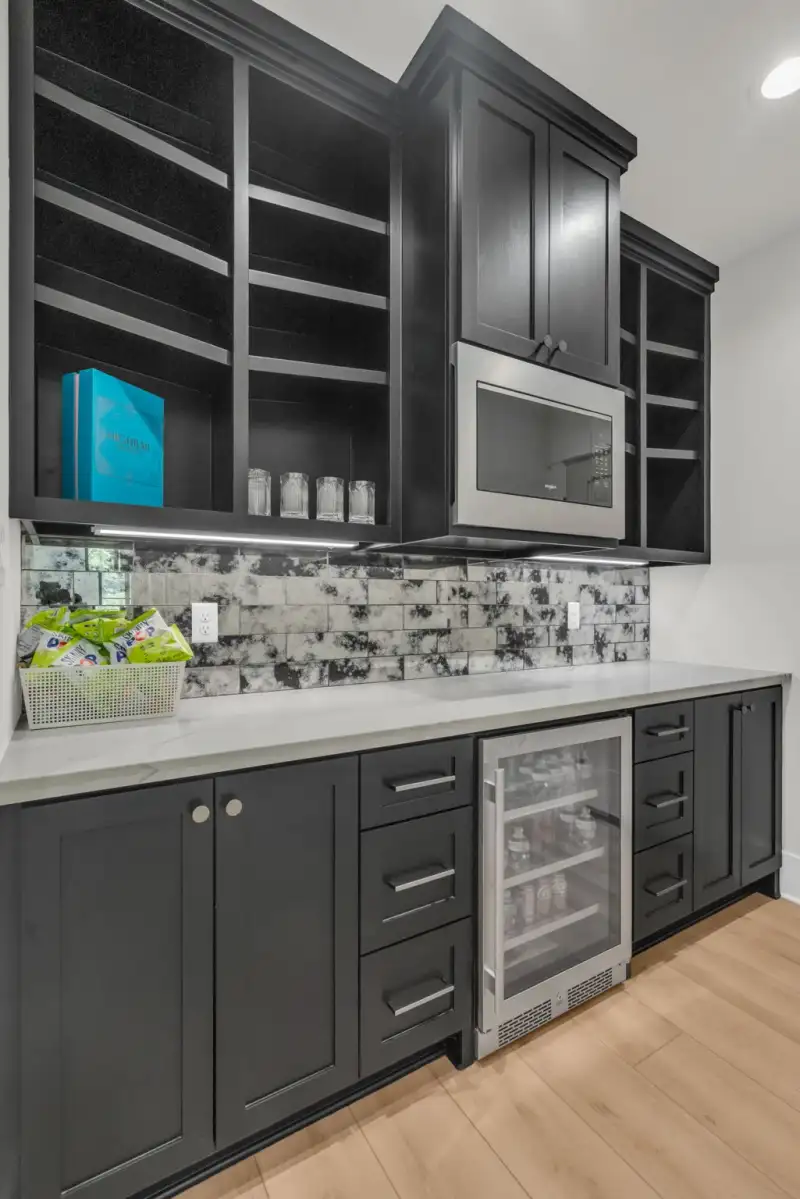 Wet bar with dark cabinets, a beverage cooler, and a mosaic tile backsplash.