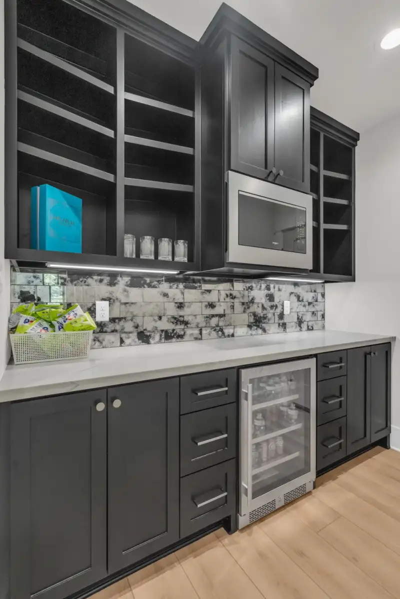Wet bar with dark cabinets, a beverage cooler, and a mosaic tile backsplash.