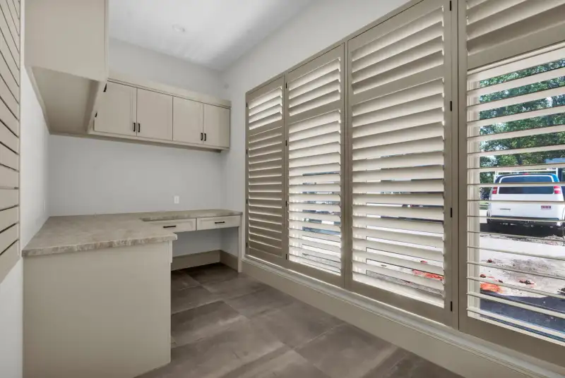 Nook with a built-in counter, wall cabinets, and plantation shutters on the windows.