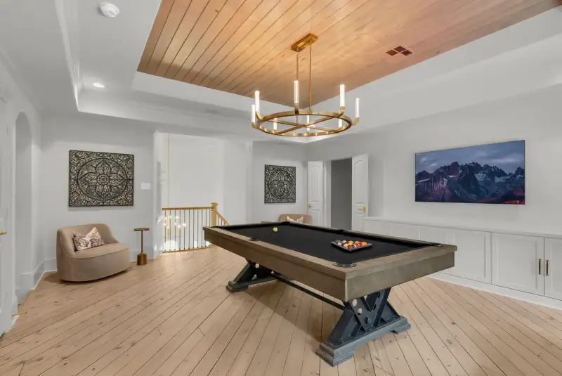 Game room with a pool table, a wood plank tray ceiling, and an open stair railing beyond.