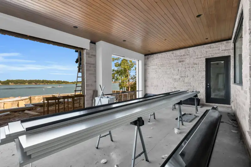 Covered patio with a wood ceiling, stone walls, and a view of the lake through an open side.