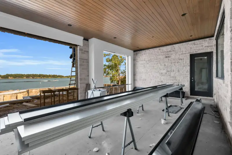 Covered patio with a wood ceiling, stone walls, and a view of the lake through an open side.