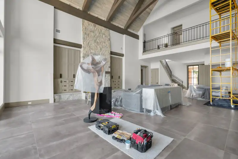 Room with a stone fireplace, a timber ceiling beam, and a balcony railing on the second level.