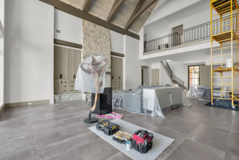 Room with a stone fireplace, a timber ceiling beam, and a balcony railing on the second level.