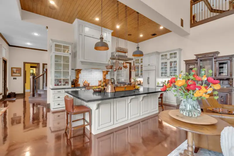 Kitchen with white cabinetry, a dark island countertop, pendant lights, and a wood-plank ceiling.