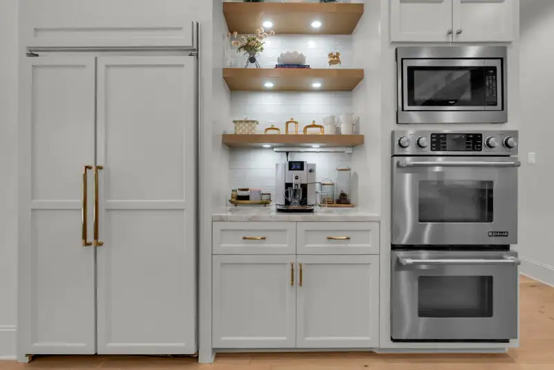 Kitchen wall with built-in refrigerator panels, open wood shelving, a microwave, and a double wall oven.