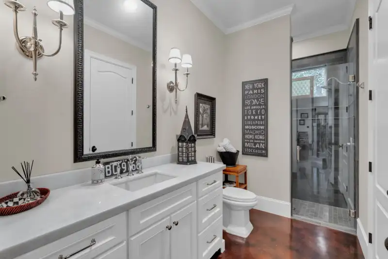 Bathroom with a white vanity, a framed mirror, wall sconces, and a glass-enclosed shower.