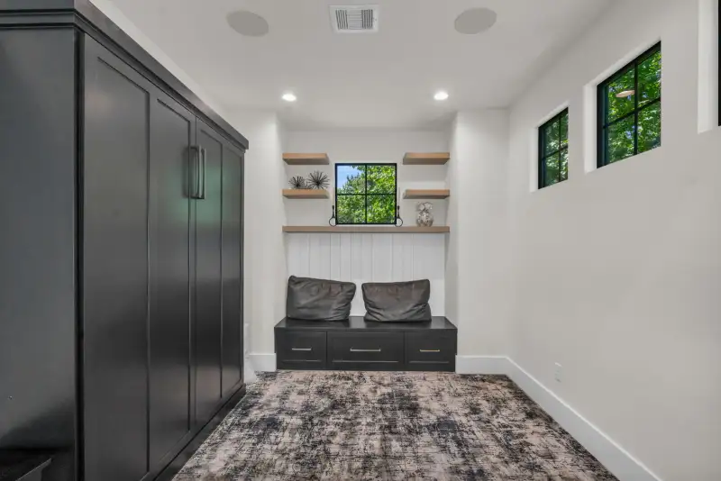 Mudroom with dark lockers, a built-in bench with cushions, and a black-framed window.