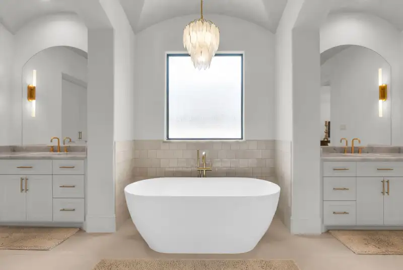 Primary bath with a freestanding tub between two vanities, each with an arched mirror.