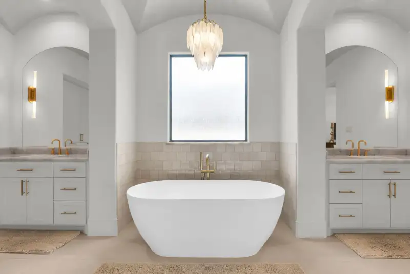 Primary bath with a freestanding tub between two vanities, each with an arched mirror.